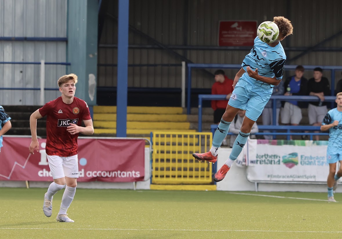 Kruz Jackson in a light-blue kit jumping to win an aerial header.